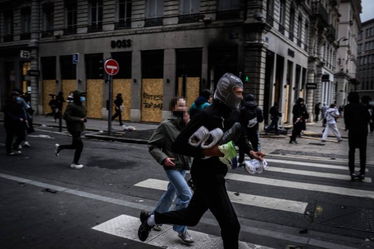 A looter runs off with shoes in front of the Boss shop, its windows already protected by boards, in Lyon’s Presqu’île, on Saturday, October 17.